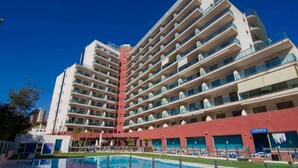 Un hôtel à plusieurs étages doté d’une piscine, de balcons et offrant une vue sur un ciel dégagé.