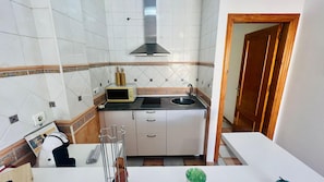 A compact kitchen with white cabinets, a black stove, a microwave, and a sink. - Apartamento Cadiz Jimena by At Home Costa del Sol (Nerja)