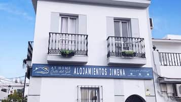 A two-story building with a sign reading "Alojamientos Jimena" and "At Home Costa del Sol".