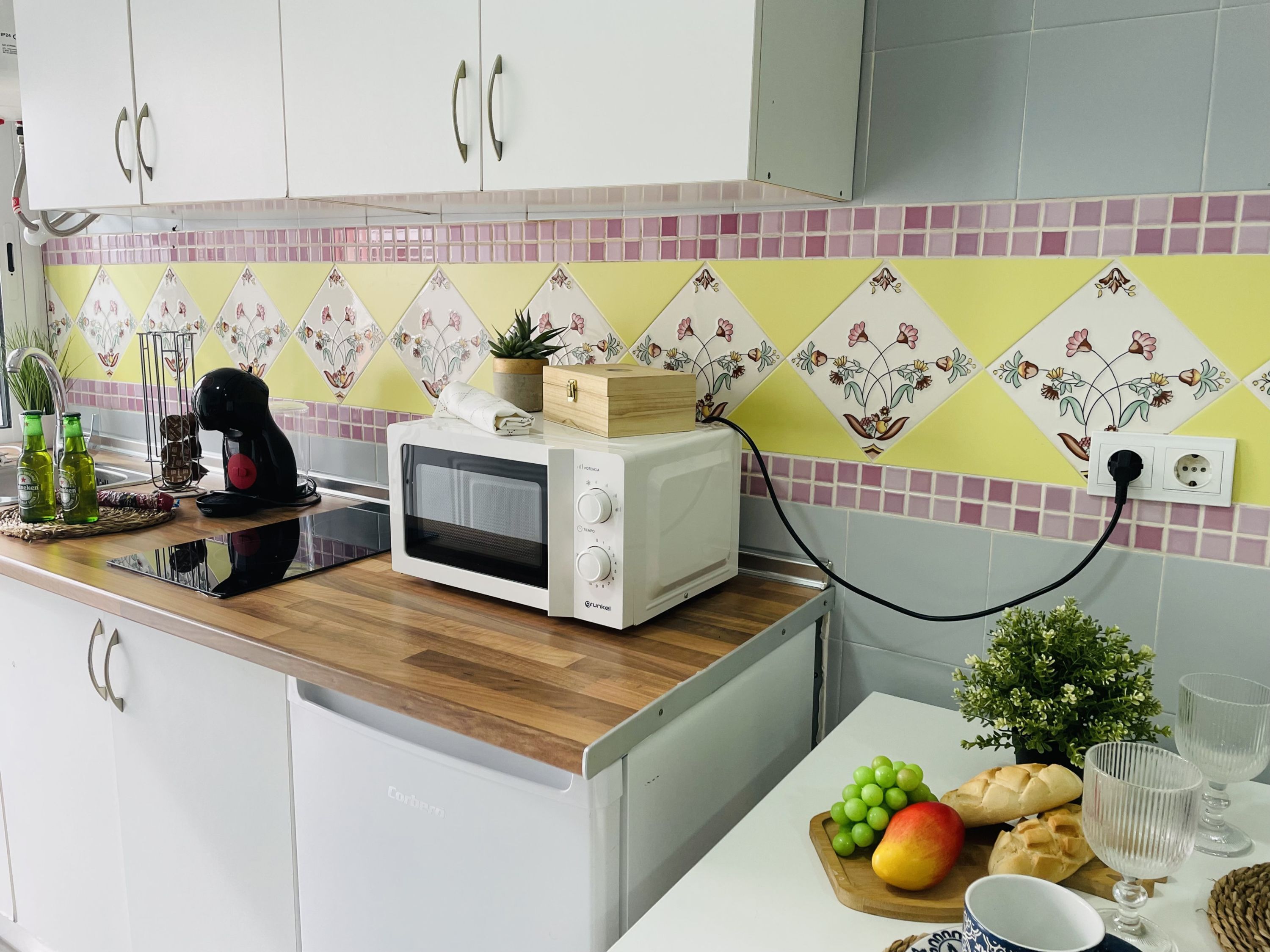 Una cocina con microondas sobre la encimera, un fregadero y un salpicadero de azulejos.