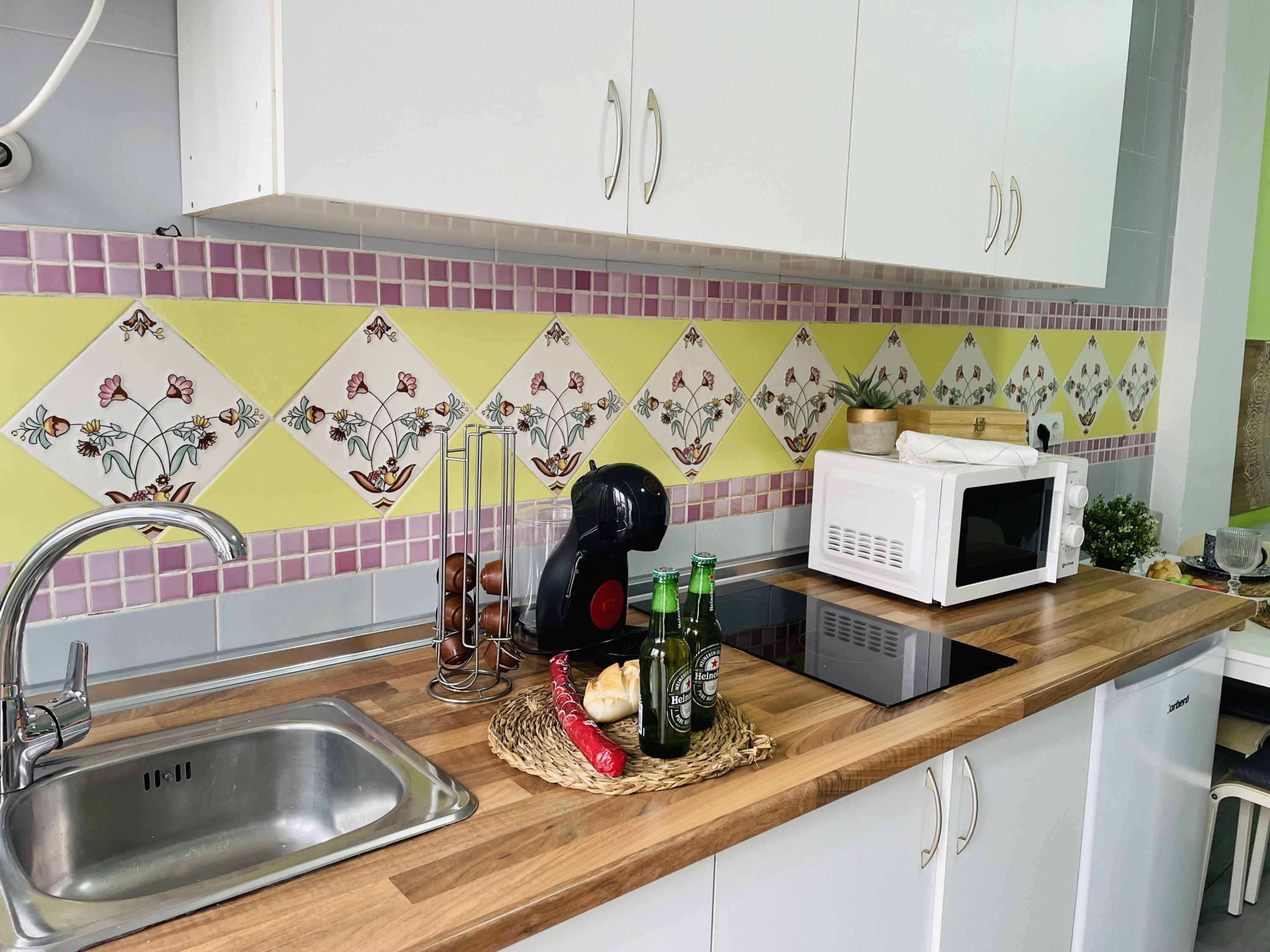 A kitchen with a stainless steel sink, a microwave, and a wooden countertop.