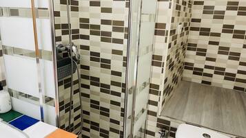 Un baño con zona de ducha, inodoro y lavabo.