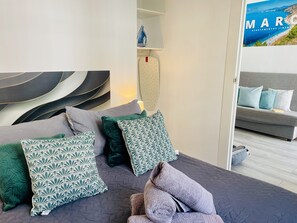 Quarto moderno com cama, almofadas, mesa de cabeceira e um pôster na parede.