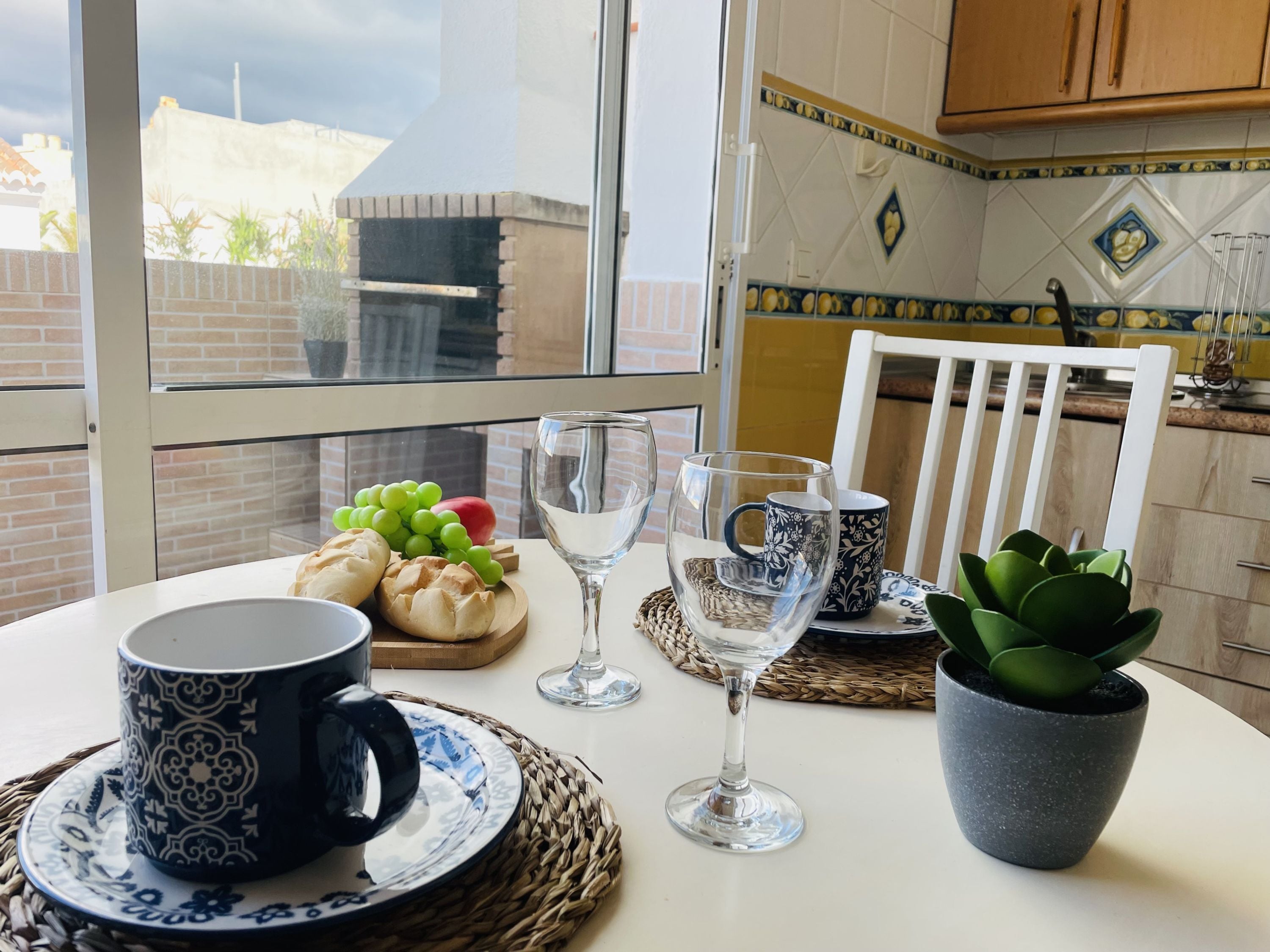 Una mesa de comedor con una taza negra, una copa de vino transparente y una planta en maceta.