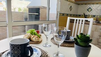 Una mesa de comedor con una taza negra, una copa de vino transparente y una planta en maceta.