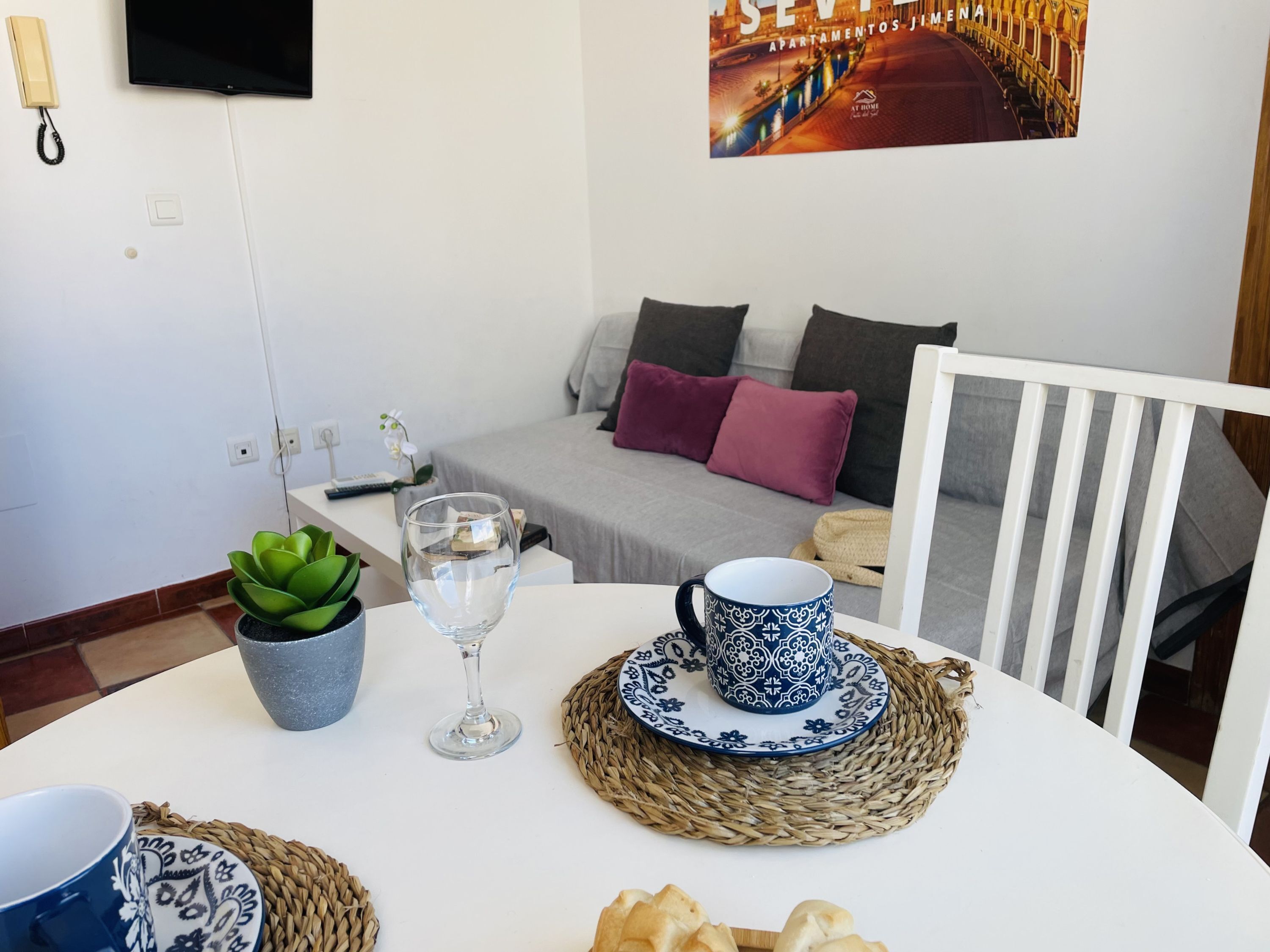 A cozy living area with a sofa, pillows, a table with a glass, a cup, and a plant.