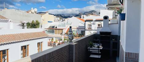 Una terraza en la azotea con un muro de ladrillo, una mesa pequeña con sillas y una planta en maceta.