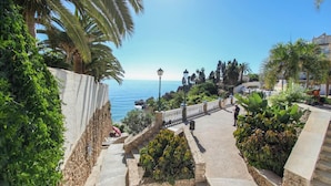 A coastal walkway with stone steps, palm trees, and a view of the sea. - Apartamento Sevilla Jimena by At Home Costa del So (Nerja)