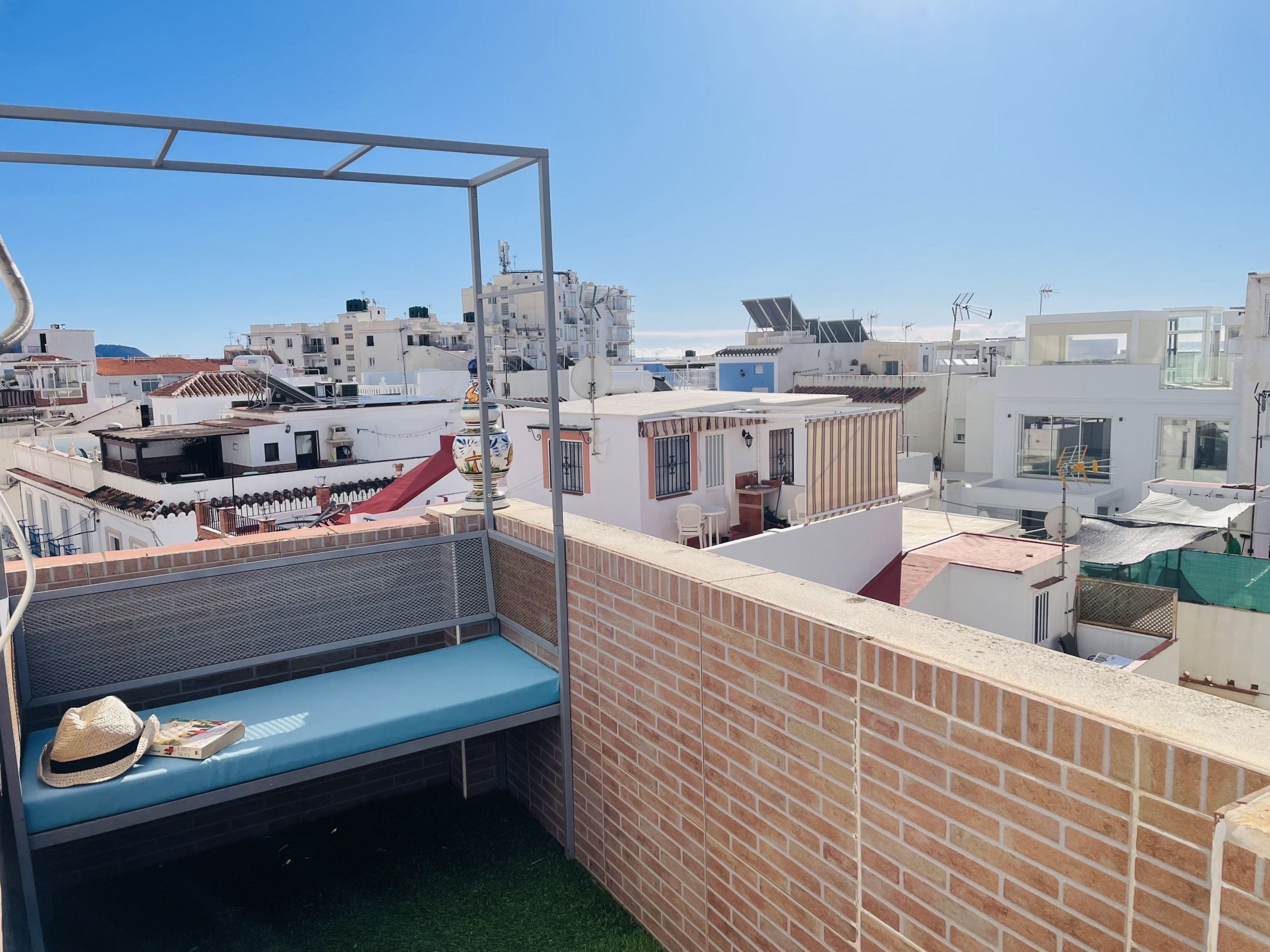 A rooftop terrace with a metal bed frame, a small table, and a chair.