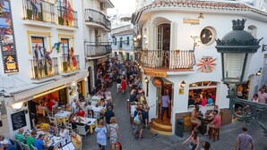 Una animada calle con terrazas en varios cafés y restaurantes.