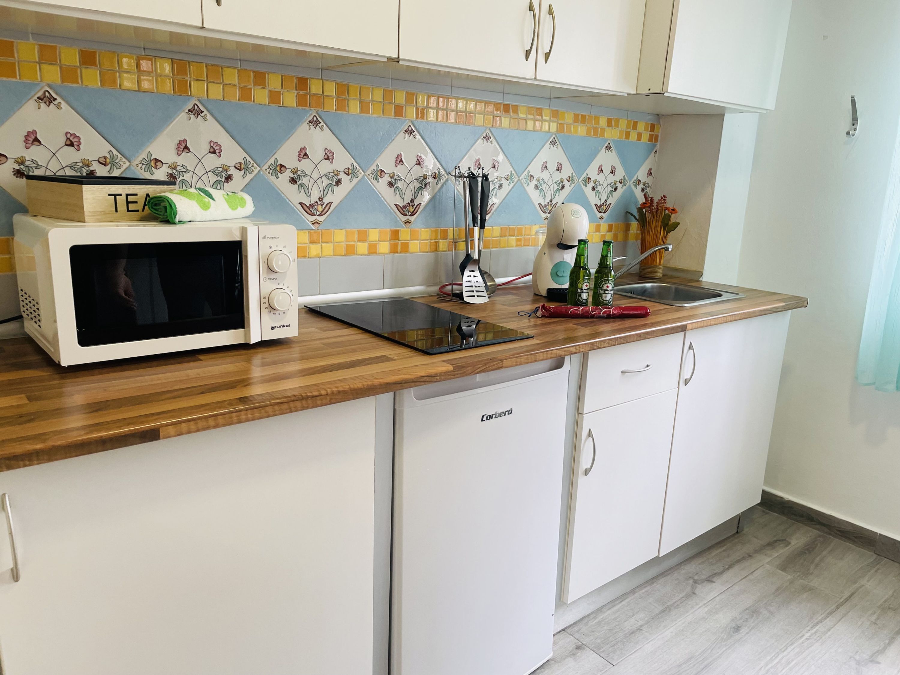 A kitchen with a microwave, a toaster, a blender, and a sink.