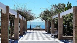 A covered walkway with brick pillars and benches, leading to a view of the sea. - Atico Granada Jimena by At Home Costa del Sol (Nerja)