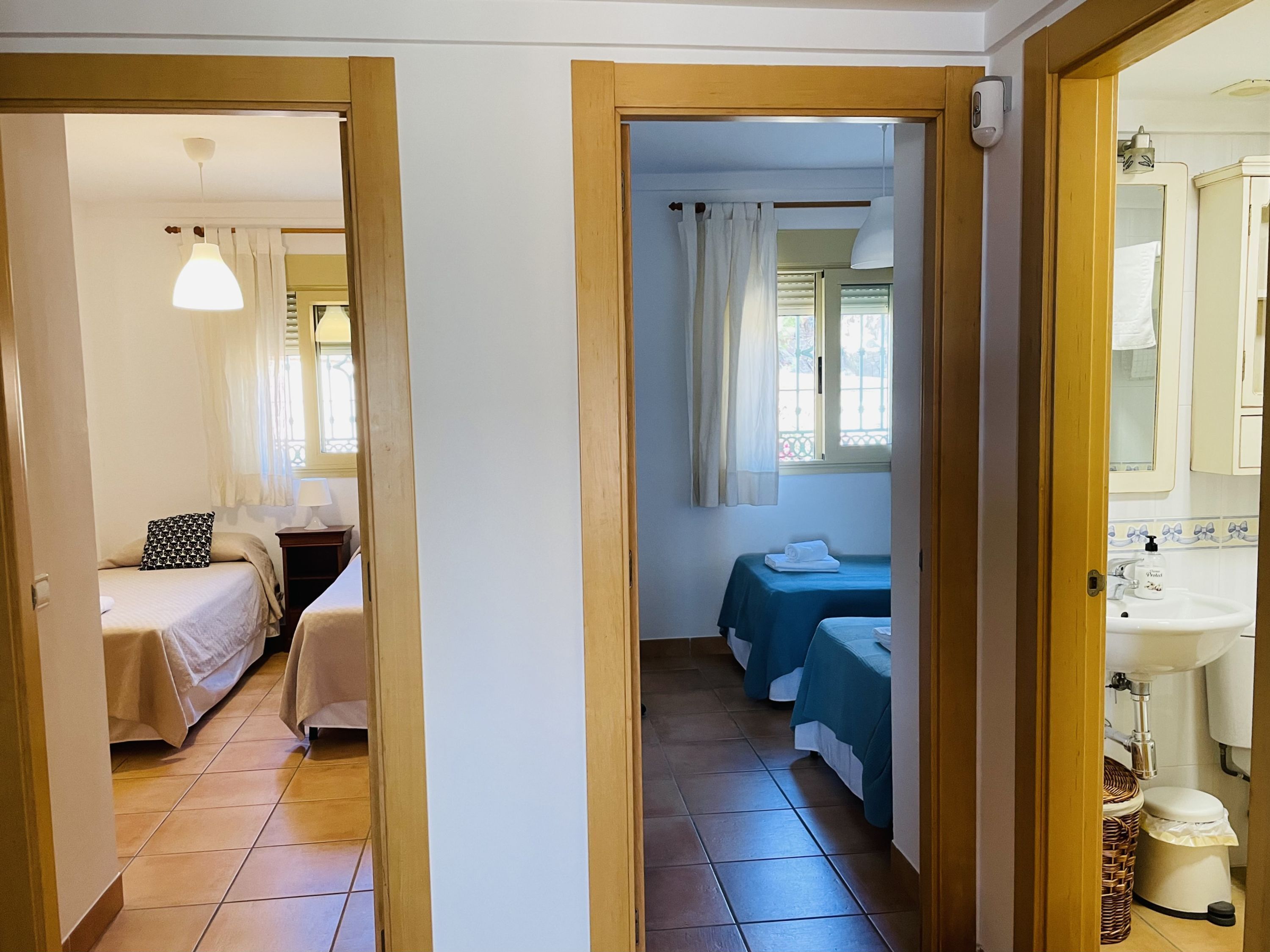 A hotel room with two beds, a bathroom, and a view of the outside.