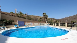 Une piscine avec des chaises longues, un drapeau et une colline en arrière-plan.