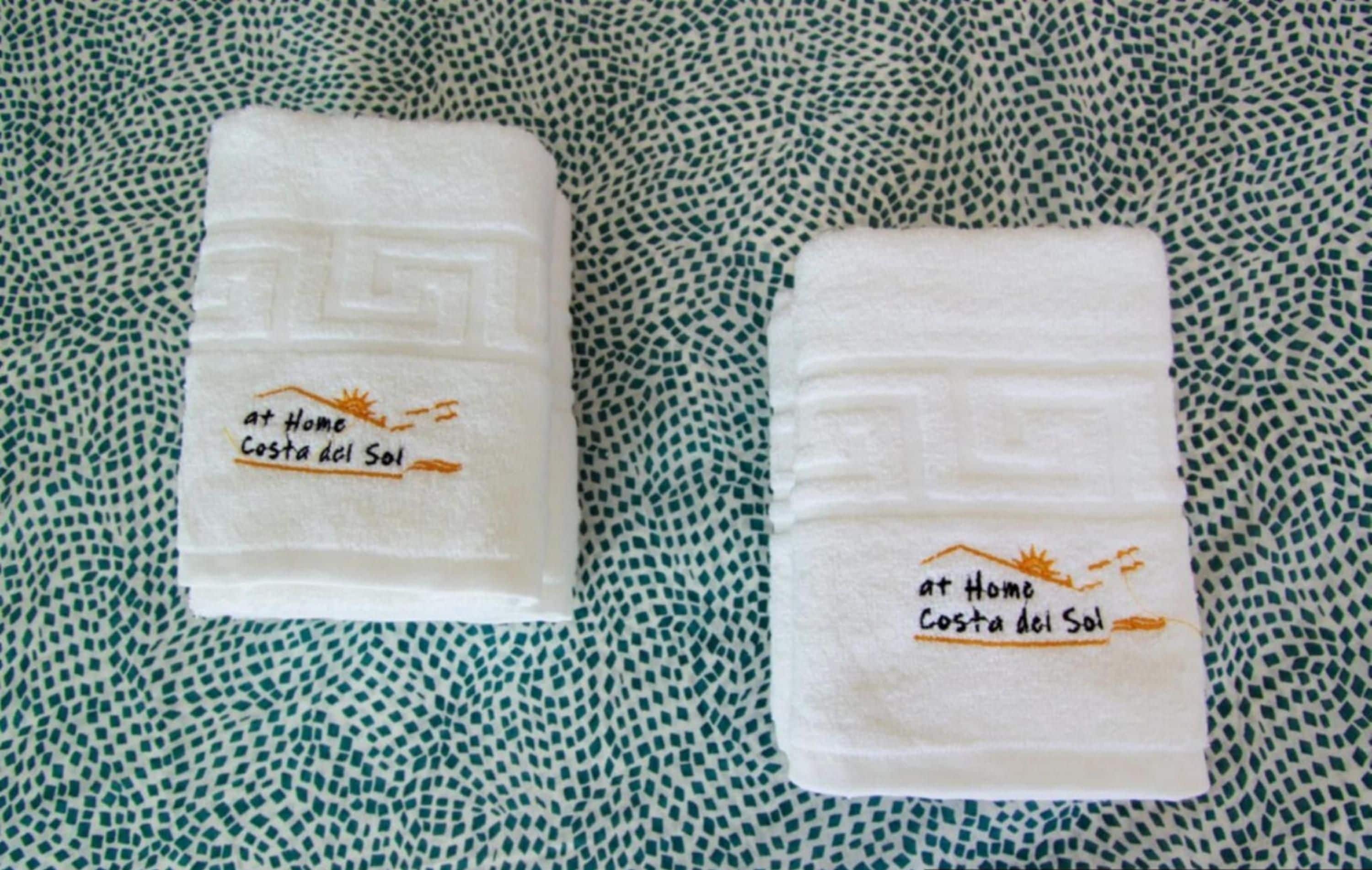 Deux serviettes blanches ornées d’un texte brodé sur un fond en tissu à motifs.
