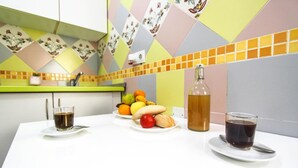 A kitchen counter with a fruit bowl, two glasses of coffee, and a bottle of water.