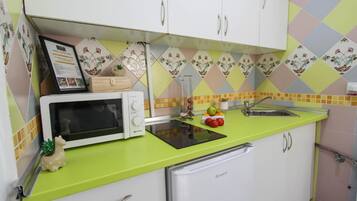 Eine kompakte Küche mit Mikrowelle, kleinem Kühlschrank und Spüle.