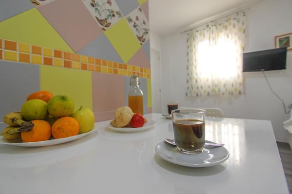 A dining table with a plate of fruit, a glass of coffee, and a bottle of water.