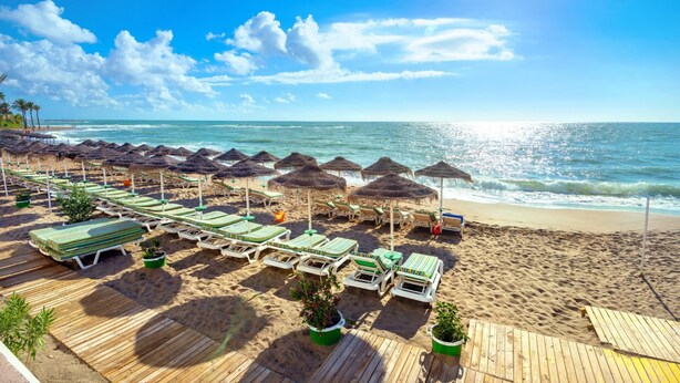 A beach with wooden deck chairs and umbrellas, a sandy beach, and the ocean. - Villa La Coscoja by At Home Costa del Sol (Torrox)