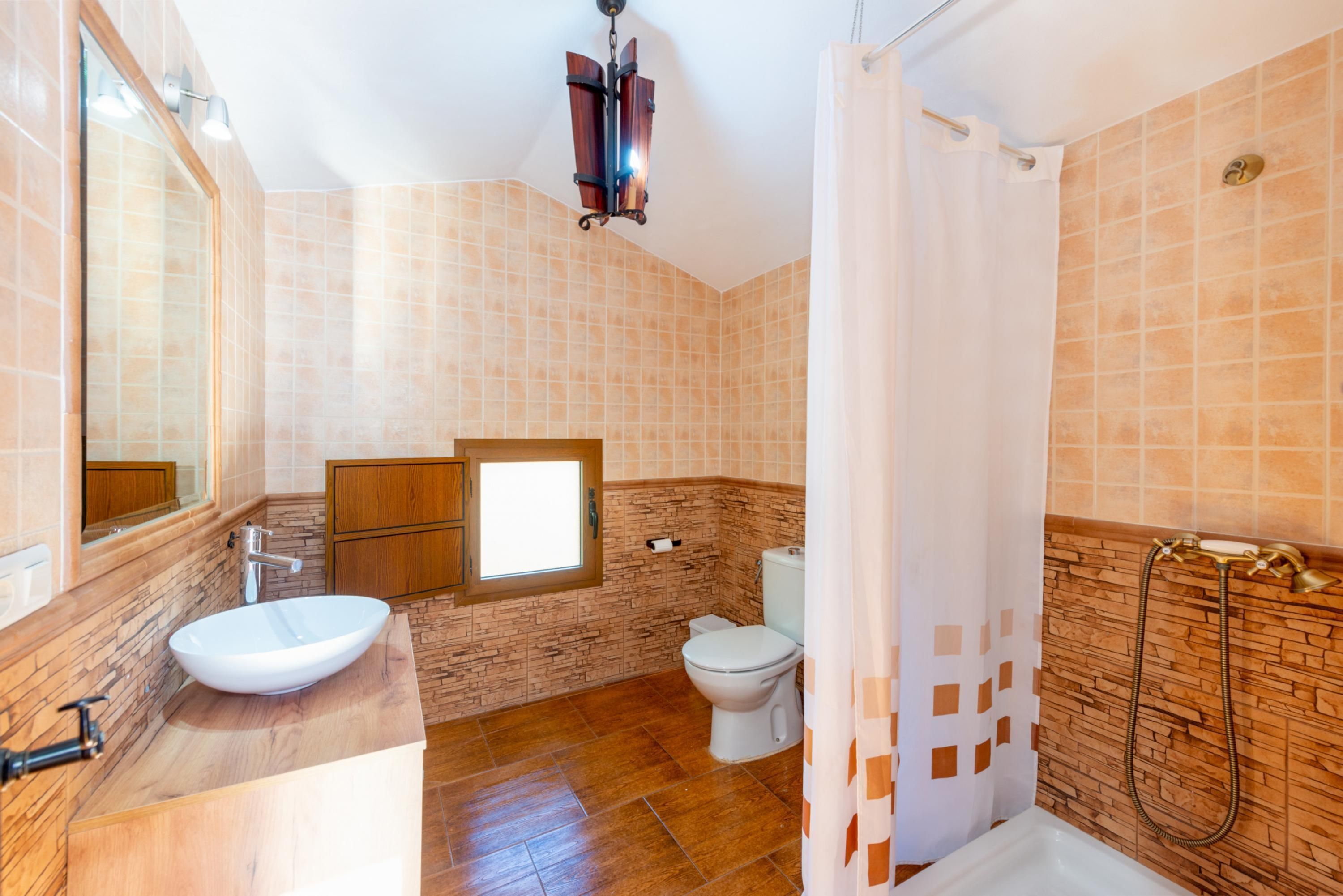 A bathroom with a large sink, toilet, and shower area.