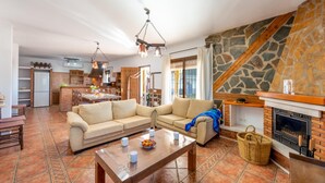 A spacious living area with a large sofa, a wooden coffee table, and a fireplace. - Villa La Coscoja by At Home Costa del Sol (Torrox)