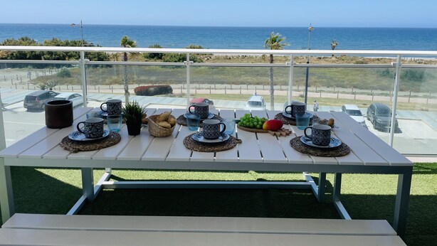 Mesa en balcón con varios objetos, con vista al mar.