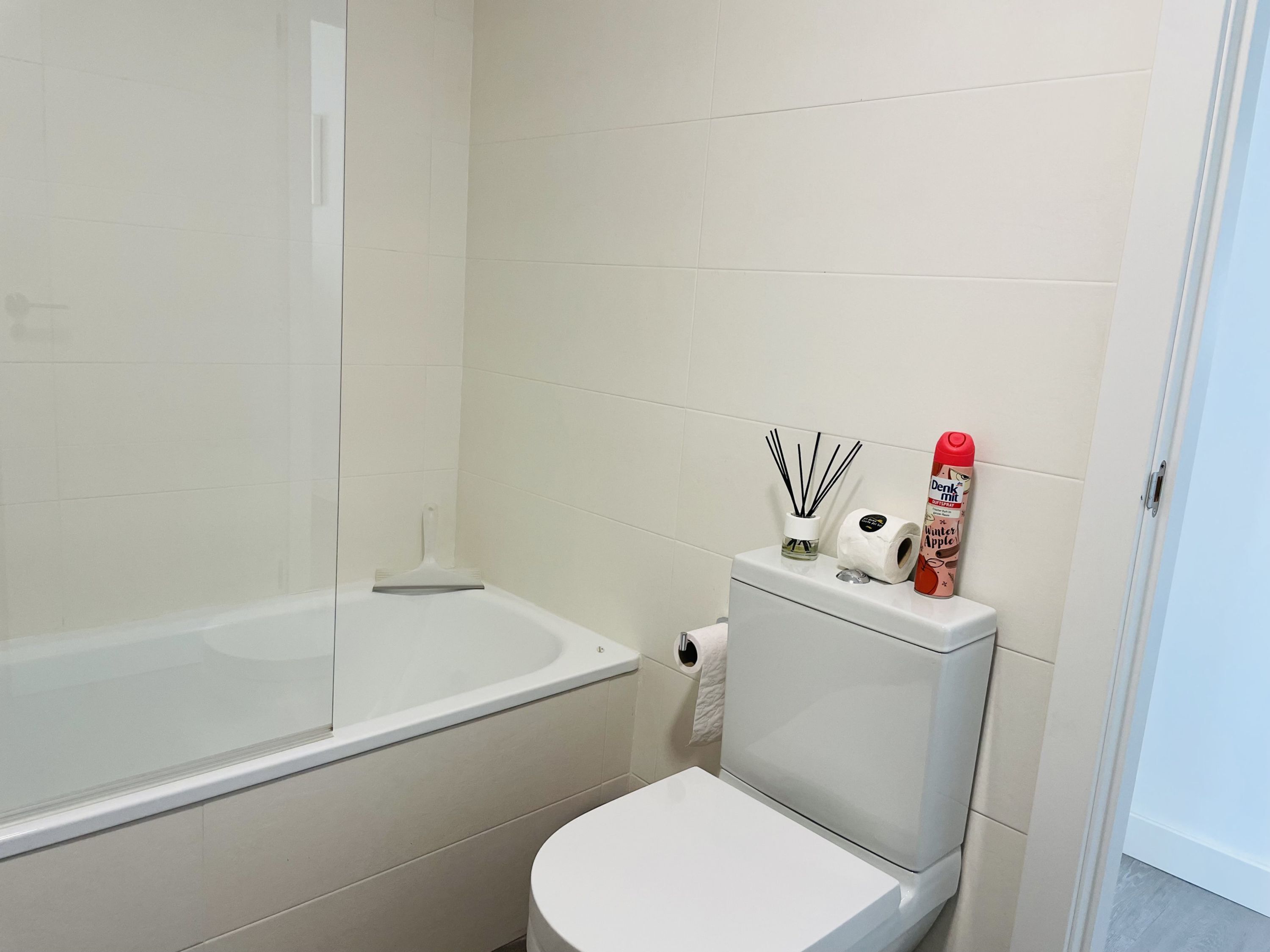 Une salle de bain équipée d’une baignoire, de toilettes et d’un porte-rouleau de papier toilette avec un rouleau de papier toilette et un flacon de désodorisant.