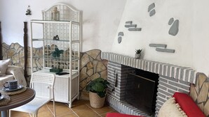 Uma sala de estar acolhedora, com uma lareira de pedra, uma estante branca e um sofá vermelho.