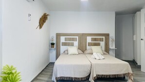 A double bed with a wooden headboard, two bedside tables with lamps, a wall-mounted air conditioner, and a potted plant. - Casa Paraiso en Frigiliana (Frigiliana)