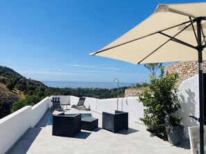 Eine Dachterrasse mit Pool, Gartenmöbeln und Meerblick.