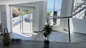 A spacious interior with large windows, a staircase, and a potted plant. - Casa Paraiso en Frigiliana (Frigiliana)