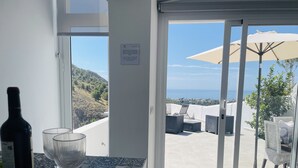 A room with a view of the sea, a bottle of wine, and two glasses on a table. - Casa Paraiso en Frigiliana (Frigiliana)