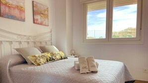 A neatly made bed with a quilted bedspread, two pillows, and two towels on the side. - Apartamento Torrox Costa a Metros de la Playa (Torrox)
