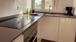 A modern kitchen with a stainless steel stove, white cabinets, a sink, and a coffee maker. - Apartamento Torrox Costa a Metros de la Playa (Torrox)