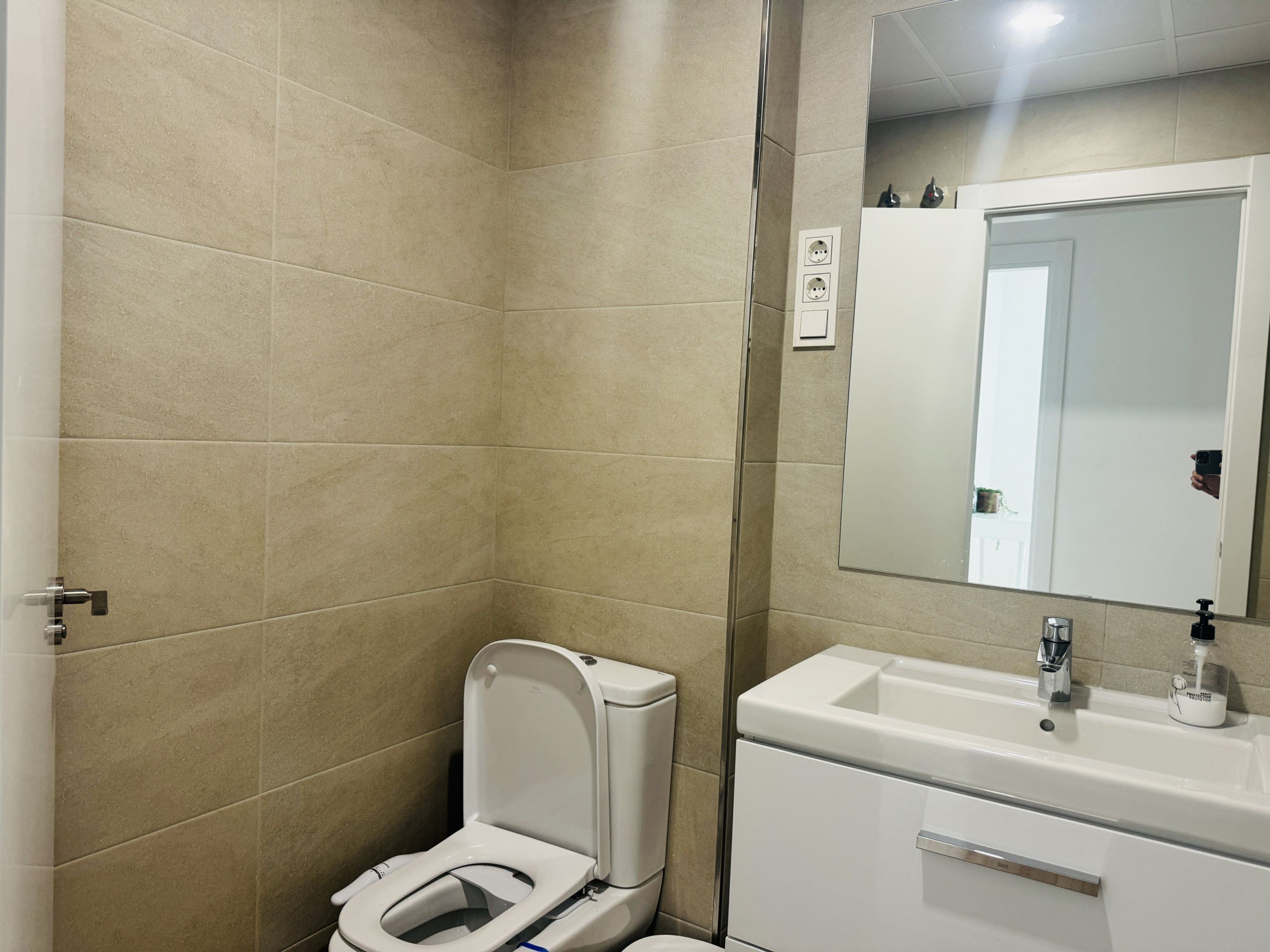 A bathroom with a toilet, sink, and mirror.