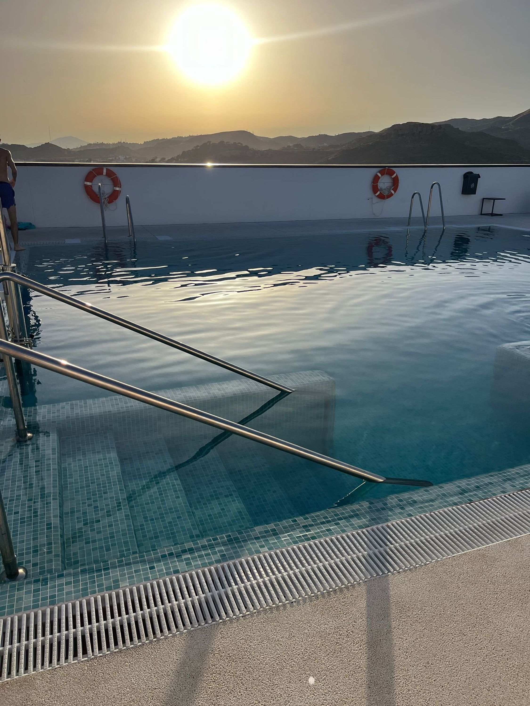 Ein Hallenbad mit klarem Wasser, Metallleitern und Rettungsringen an den Wänden.