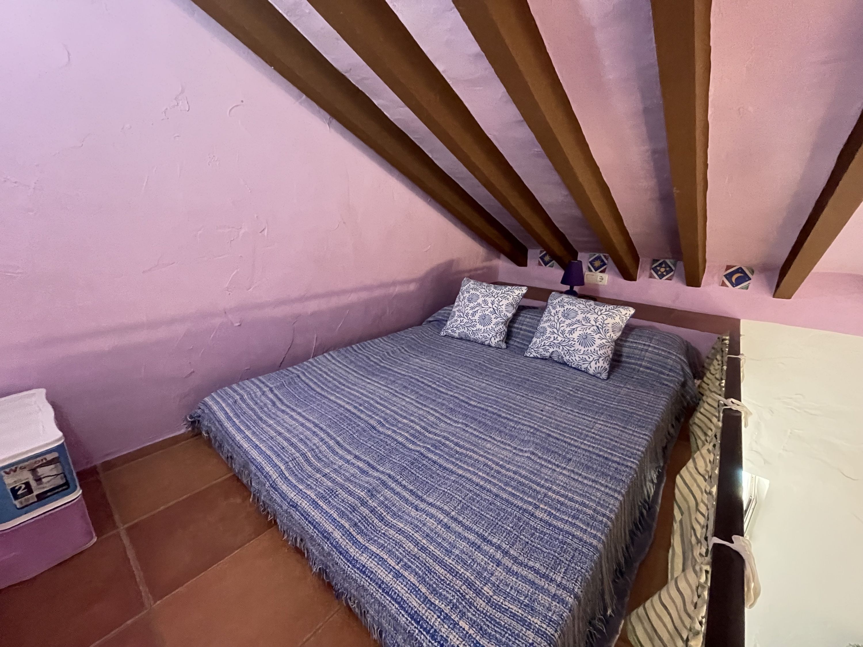 Une chambre à coucher avec un lit, des oreillers, une table de chevet et un mur orné de carreaux décoratifs.