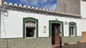 A building with a tiled facade, a wooden door, and a small window with a metal grille. - Casa Paquita con Piscina Privada en Maro By At Hom (Nerja)