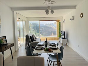 Un comedor con una mesa dispuesta para dos personas, un sofá y un mueble para la televisión.