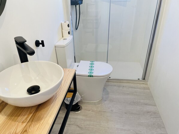 Un baño con lavamanos blanco, inodoro y ducha.