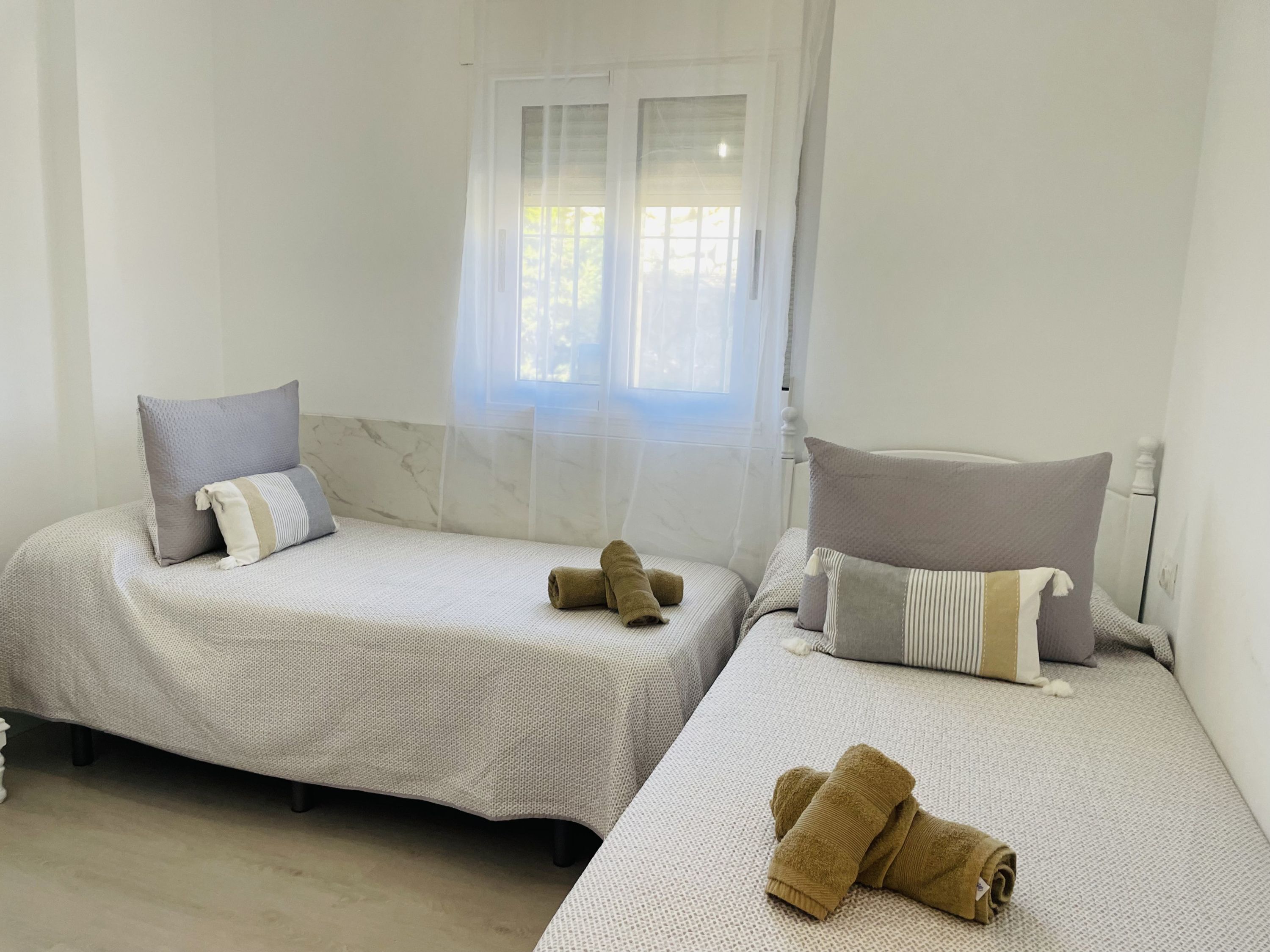 Ein Zimmer mit zwei Betten, jeweils mit einem Kopfkissen und einem zusammengerollten Handtuch.