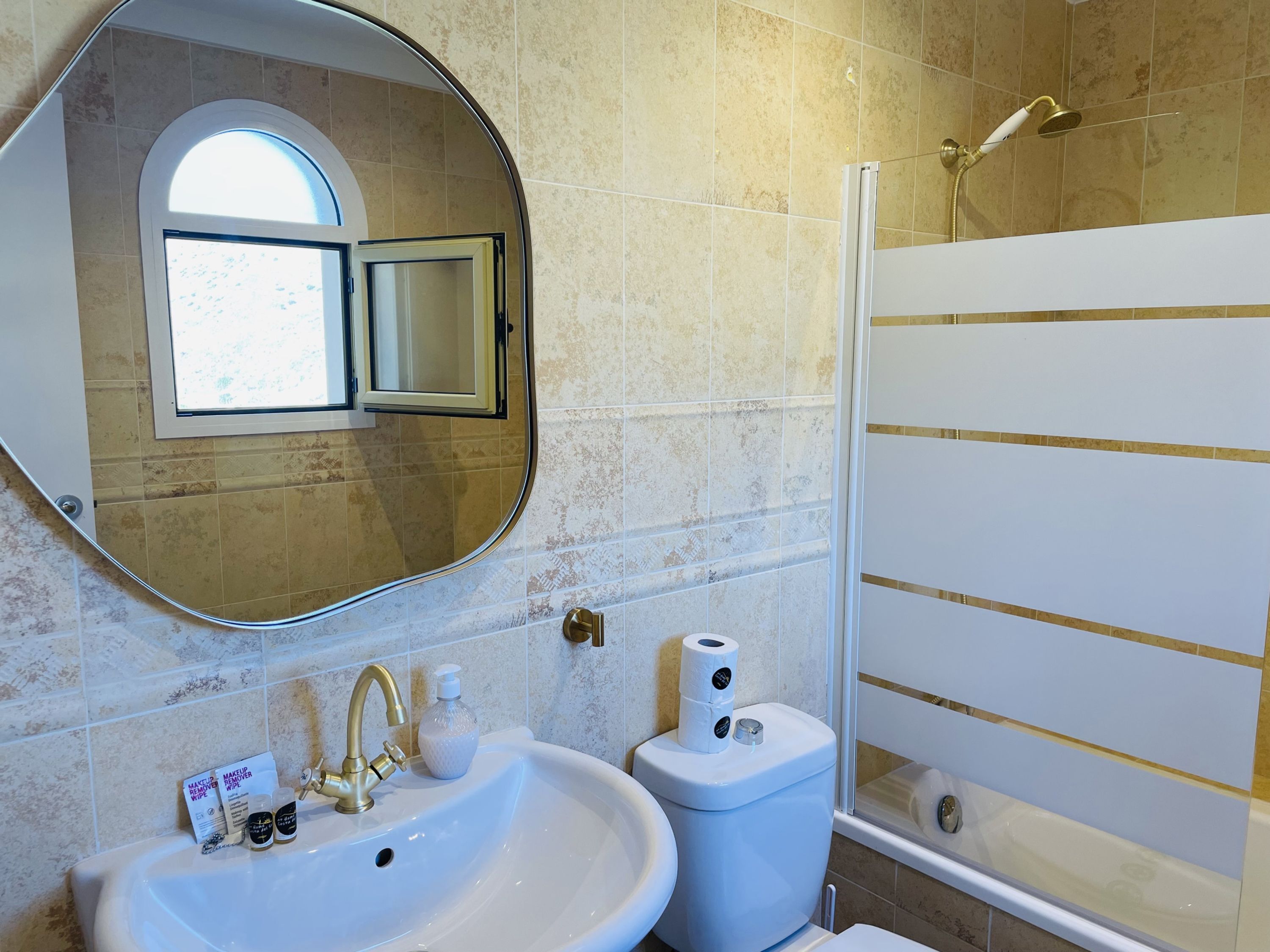 A bathroom with a sink, mirror, toilet, and shower.