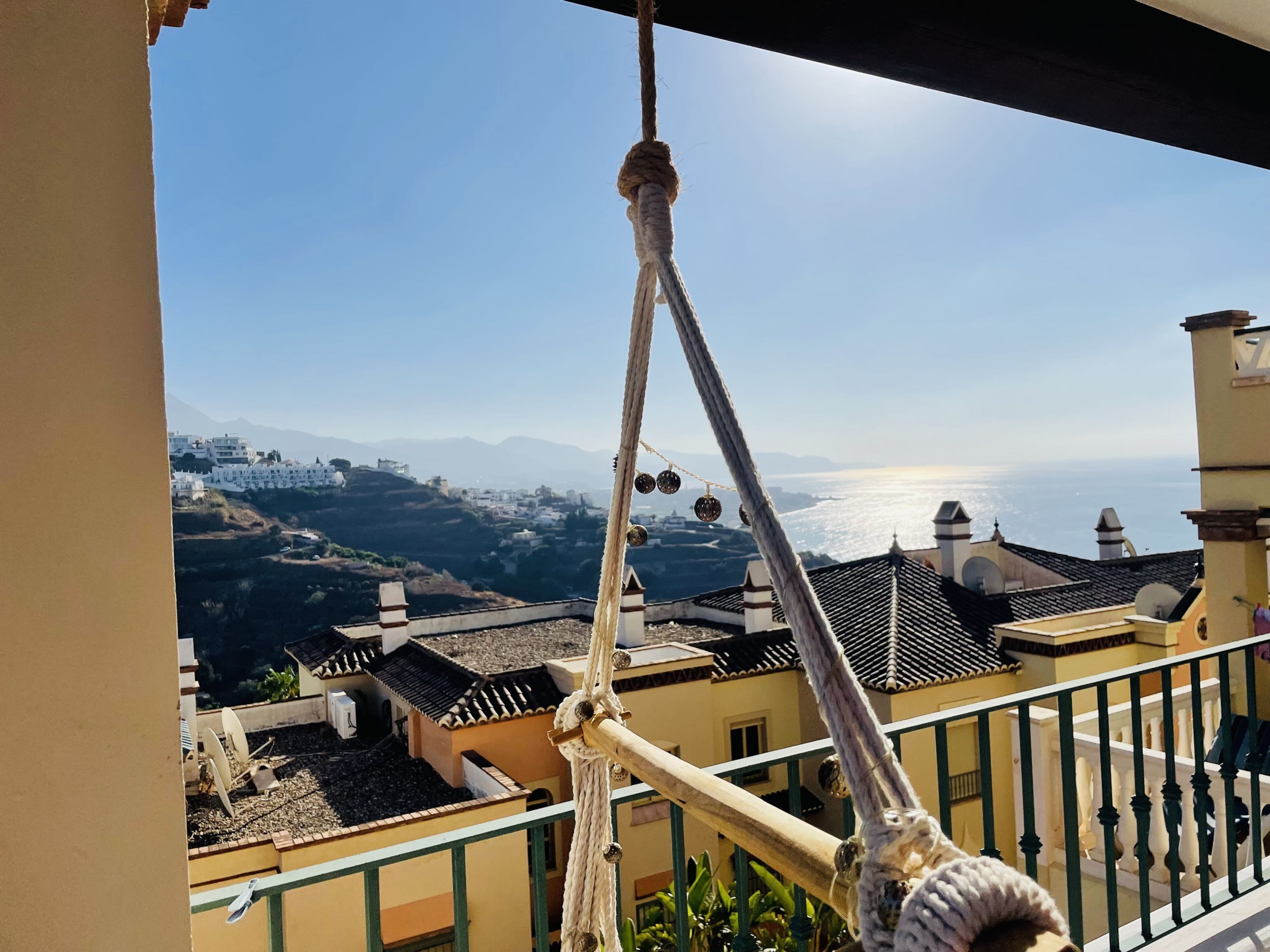 A balcony with a view of a coastal town and mountains.