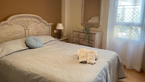 A bedroom with a bed, a nightstand, a dresser, a mirror, and a window with a view. - Apartamento Cantarero by At Home Costa del sol (Nerja)