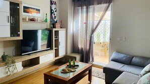 A living room with a flat-screen TV, wooden cabinets, a glass coffee table, and a gray sofa. - Apartamento Cantarero by At Home Costa del sol (Nerja)