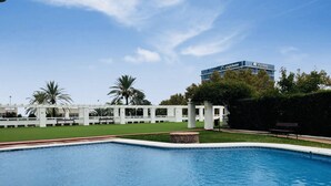 Una piscina con solarium bianco, palme e un edificio sullo sfondo con un cartello 'singlehome'.