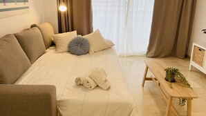 Una camera accogliente con un letto, cuscini, un comodino con una pianta e un'opera d'arte a parete.