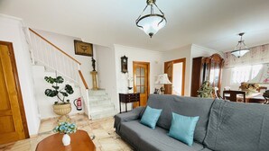 A living room with a gray sofa, wooden coffee table, and a staircase with white railings.
