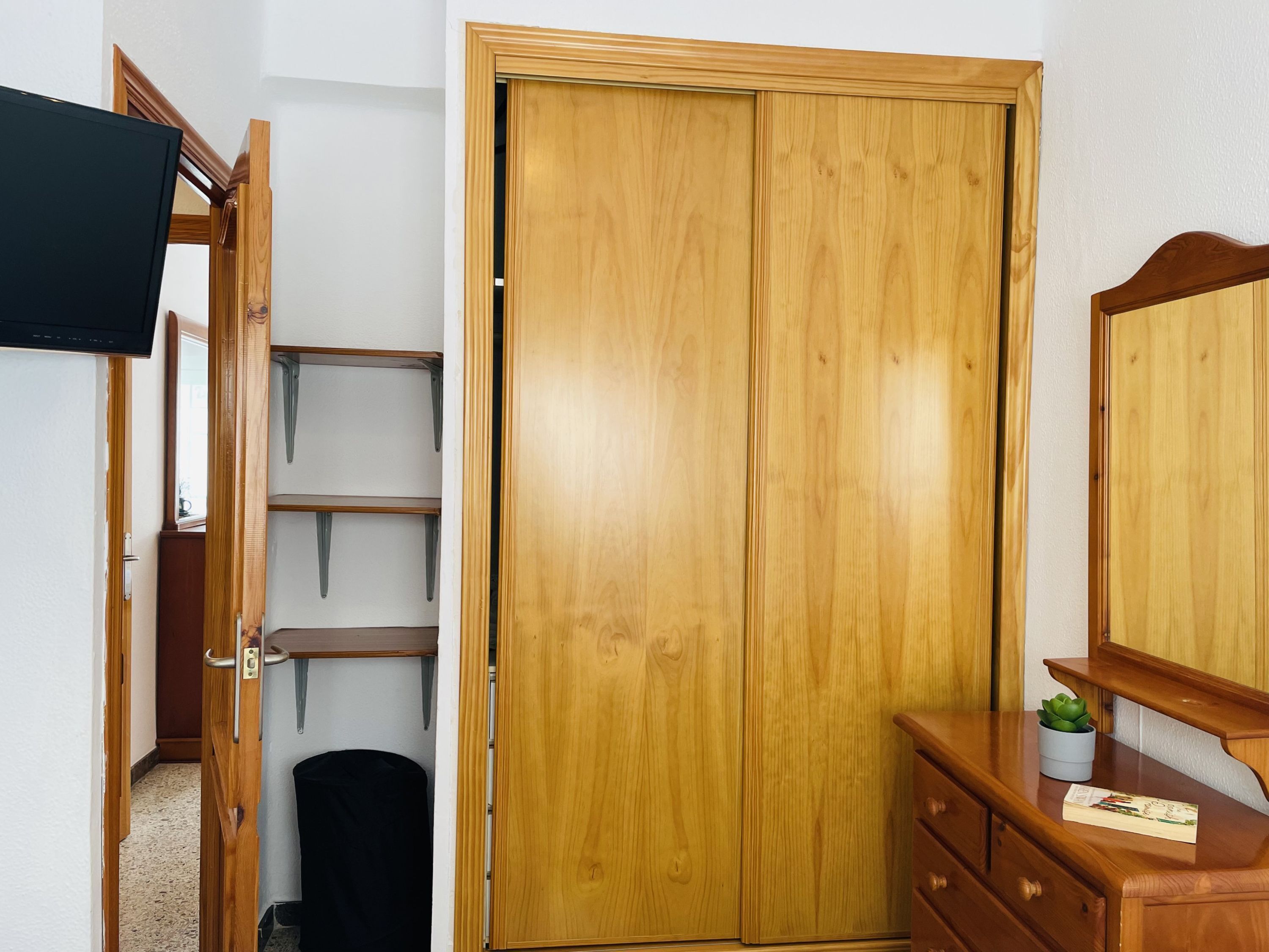 Une armoire en bois avec un miroir, une petite étagère et un tiroir.