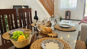 Una mesa de comedor con platos, vasos, una botella y una cesta de fruta.